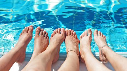 Drei Frauen halten in Berlin ihre Füße ins kühlende Wasser.
